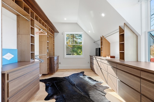 spacious closet with light hardwood / wood-style flooring and vaulted ceiling