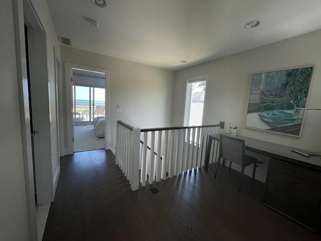 hallway with an upstairs landing, recessed lighting, visible vents, and wood finished floors