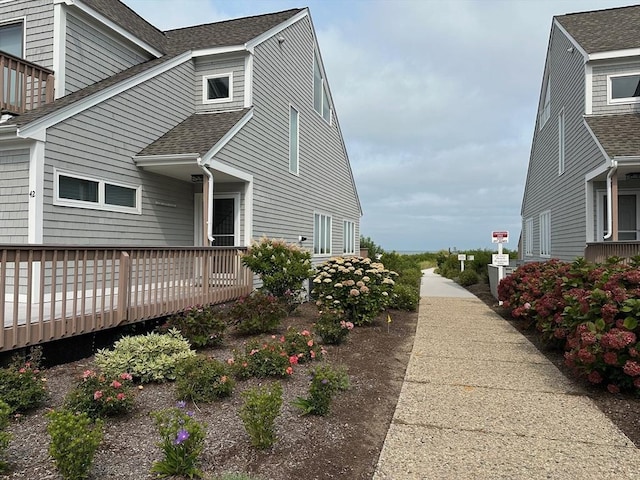 view of side of home with a wooden deck and a shingled roof