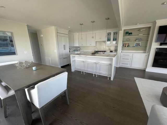 kitchen with white cabinetry, dark wood-style flooring, light countertops, and a breakfast bar area