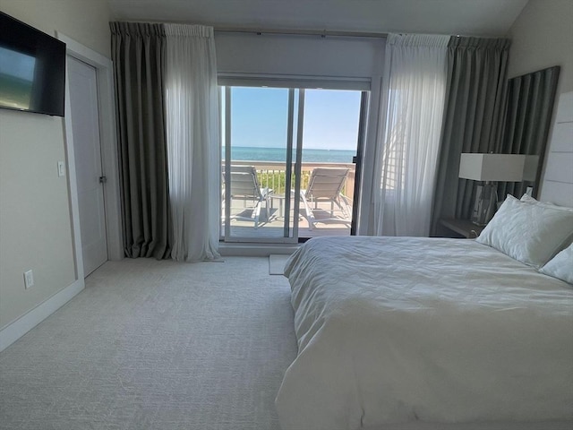 carpeted bedroom with a water view, baseboards, and access to exterior