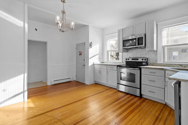 kitchen featuring pendant lighting, backsplash, a baseboard heating unit, light hardwood / wood-style floors, and stainless steel appliances