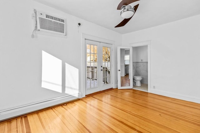 empty room with wood-type flooring, a wall mounted air conditioner, ceiling fan, and french doors