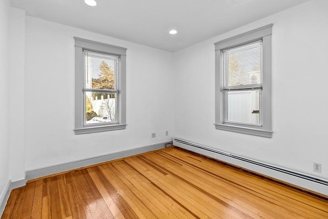 unfurnished room with hardwood / wood-style floors and a baseboard heating unit