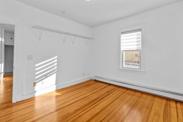 spare room featuring a baseboard heating unit and light hardwood / wood-style flooring