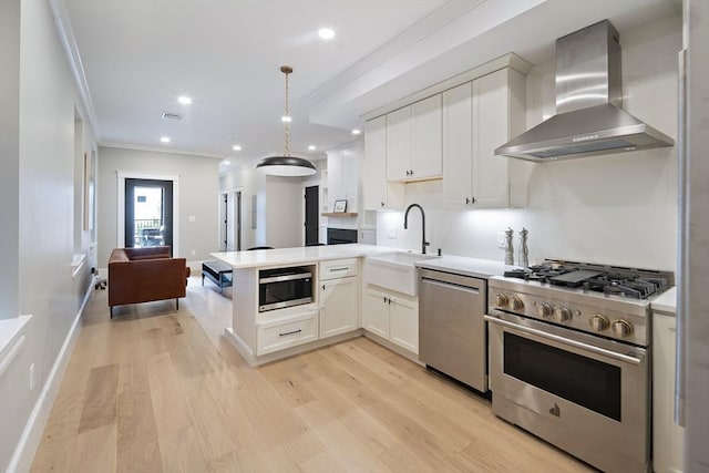 40 Mount Vernon St Unit 2, Boston, MA 02129 - kitchen with wall chimney exhaust hood, stainless steel appliances, ornamental molding, light wood finished floors, and white cabinetry