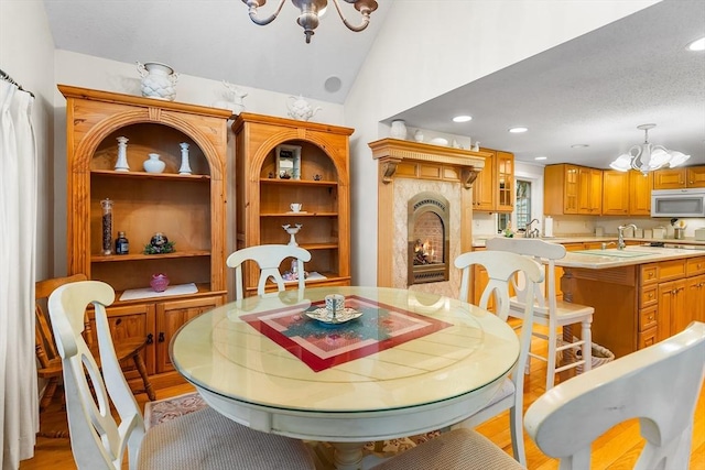 11 Bayside Dr, Wales, MA 01081 - dining area with a chandelier, a lit fireplace, light wood-type flooring, recessed lighting, and lofted ceiling
