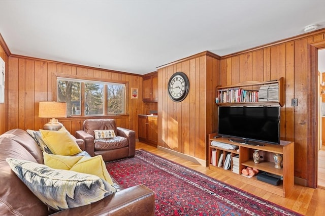 living room with crown molding, wood walls, and light wood-type flooring