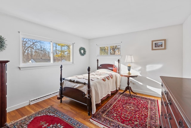 bedroom featuring hardwood / wood-style floors and a baseboard heating unit