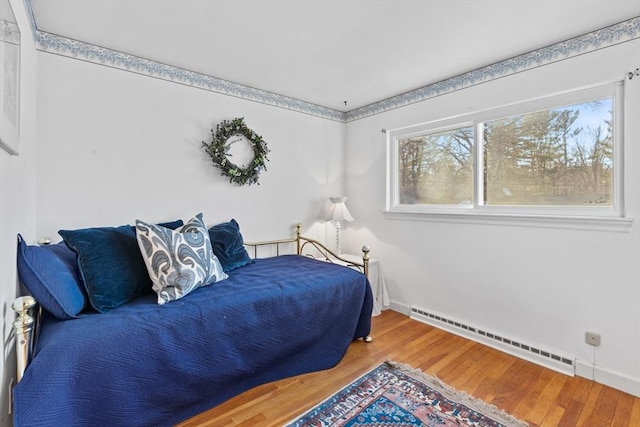 bedroom featuring hardwood / wood-style flooring and a baseboard heating unit