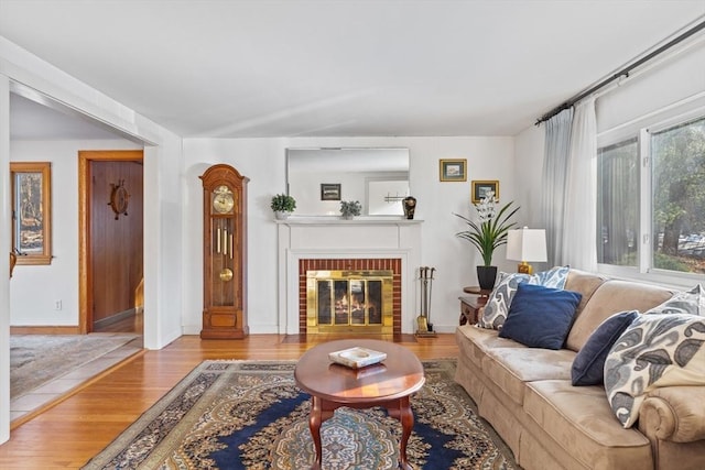 living room featuring a brick fireplace and light hardwood / wood-style flooring