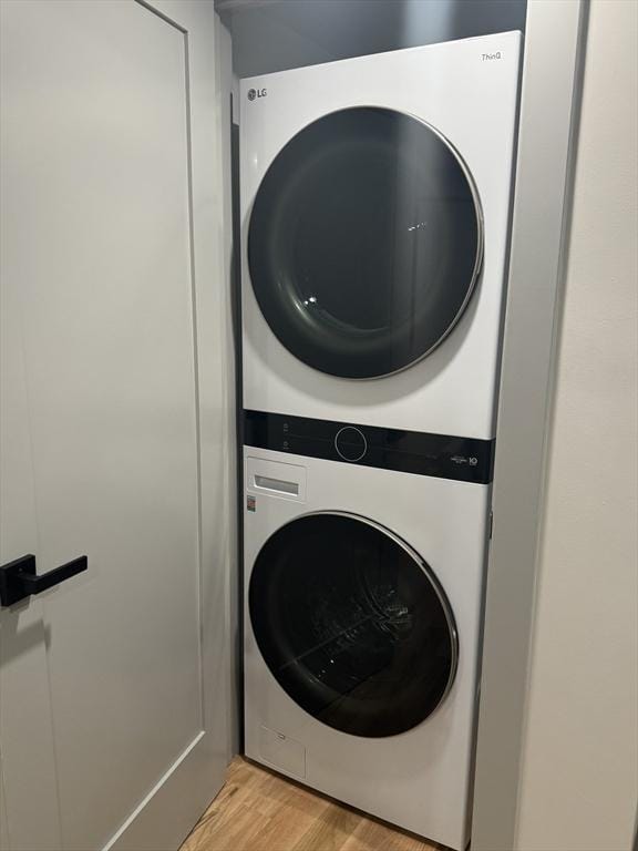 washroom featuring stacked washing maching and dryer and light hardwood / wood-style floors