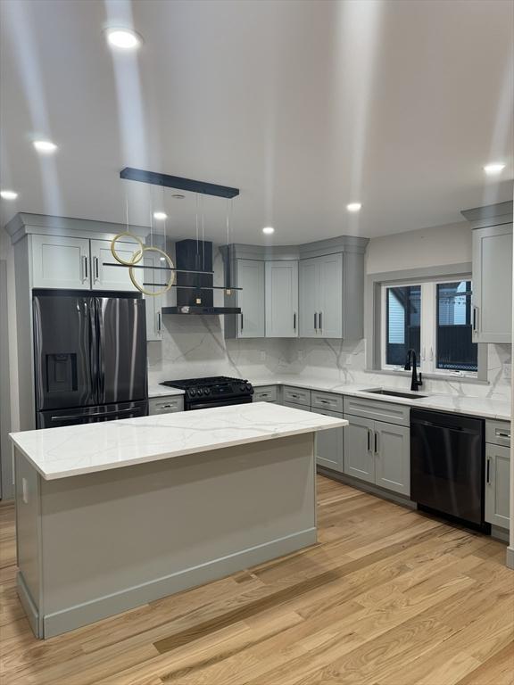 kitchen featuring gray cabinetry, wall chimney range hood, sink, and black appliances