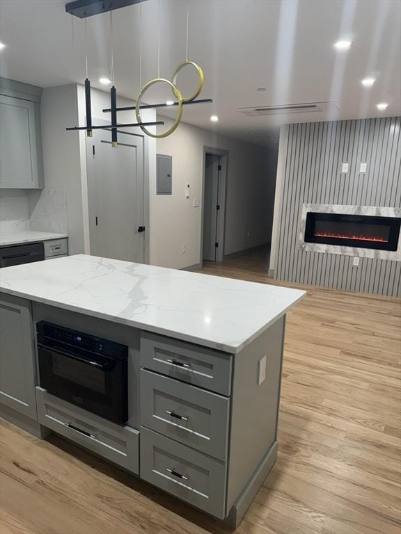 kitchen featuring gray cabinetry, hanging light fixtures, electric panel, a kitchen island, and oven