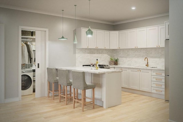 kitchen featuring a breakfast bar, light wood-style floors, washer / clothes dryer, and decorative backsplash