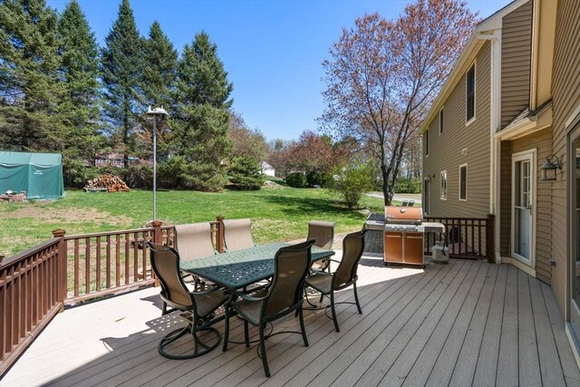 deck featuring outdoor dining space, a yard, and grilling area