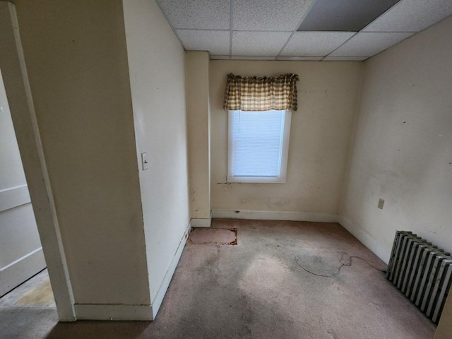 spare room featuring radiator heating unit and a drop ceiling