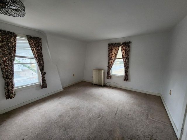 empty room with carpet flooring, radiator heating unit, and plenty of natural light