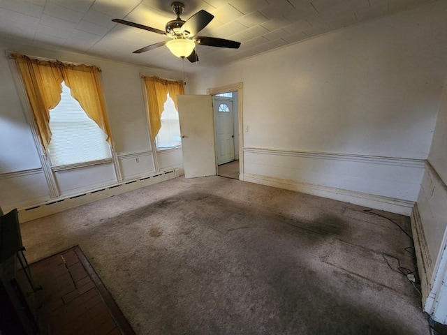 carpeted empty room featuring a baseboard radiator and ceiling fan