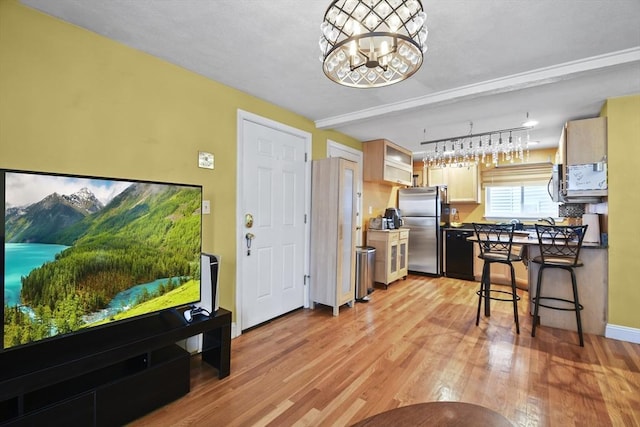 kitchen featuring light hardwood / wood-style floors, light brown cabinetry, stainless steel refrigerator, and an inviting chandelier