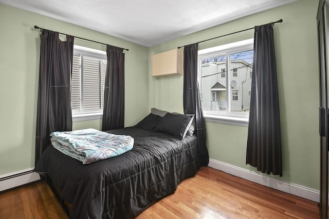 bedroom featuring wood-type flooring and a baseboard radiator