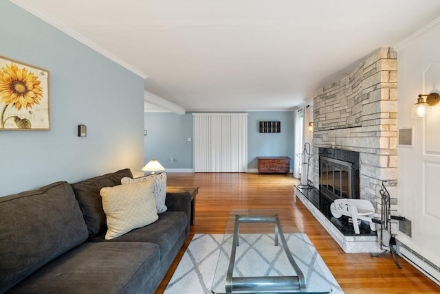 living room with hardwood / wood-style flooring, crown molding, baseboard heating, and a fireplace