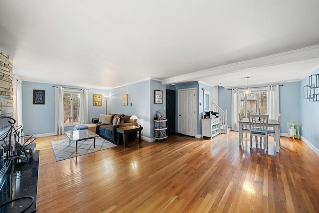 living room with light hardwood / wood-style flooring, ornamental molding, and a fireplace