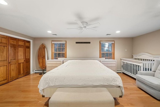 bedroom with light hardwood / wood-style floors, ceiling fan, and baseboard heating