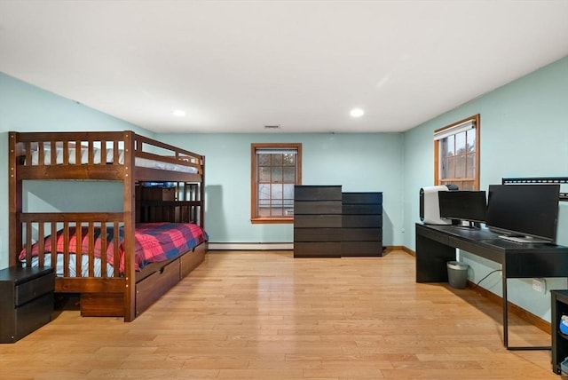 bedroom with a baseboard heating unit and light hardwood / wood-style flooring