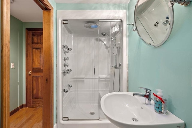 bathroom with a shower with shower door, sink, and hardwood / wood-style flooring