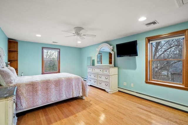 bedroom with ceiling fan, light wood-type flooring, and a baseboard heating unit