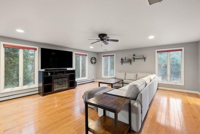 living room featuring plenty of natural light, a baseboard heating unit, and light hardwood / wood-style floors