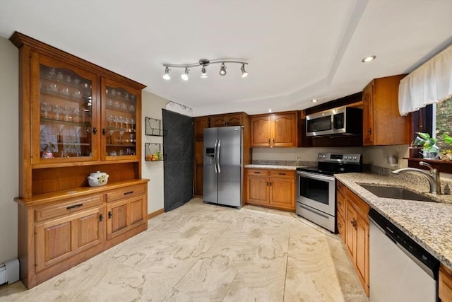 kitchen with sink, light stone counters, baseboard heating, and stainless steel appliances