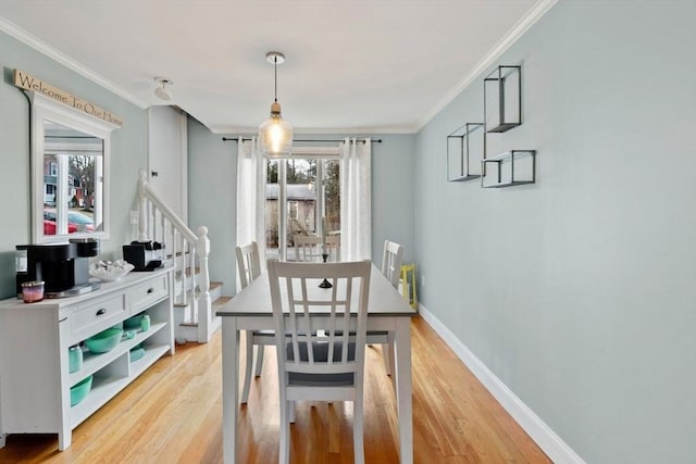 dining area with light hardwood / wood-style flooring and ornamental molding