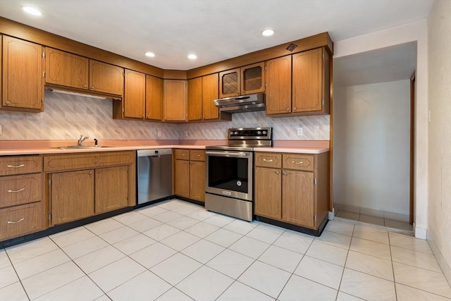 kitchen featuring stainless steel appliances, under cabinet range hood, brown cabinetry, light countertops, and recessed lighting