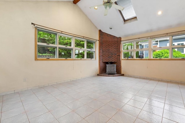 unfurnished living room featuring a skylight, a ceiling fan, high vaulted ceiling, a wood stove, and light tile patterned floors