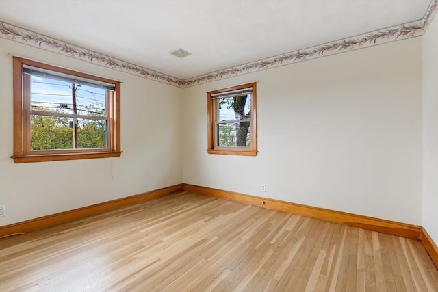 spare room with baseboards, healthy amount of natural light, and light wood-style flooring