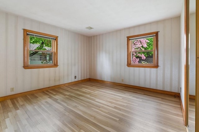 unfurnished room with plenty of natural light, light wood finished floors, and baseboards