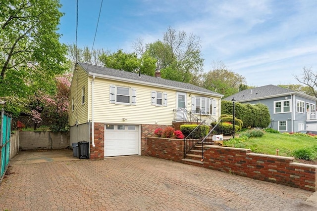 view of front of home featuring driveway, a chimney, and a garage