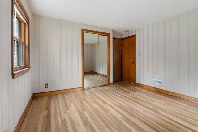 unfurnished room with light wood finished floors, baseboards, and wallpapered walls