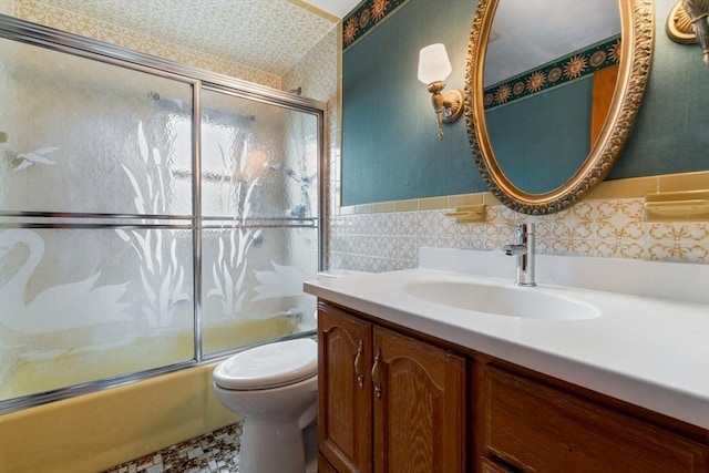bathroom with tile walls, toilet, shower / bath combination with glass door, and vanity