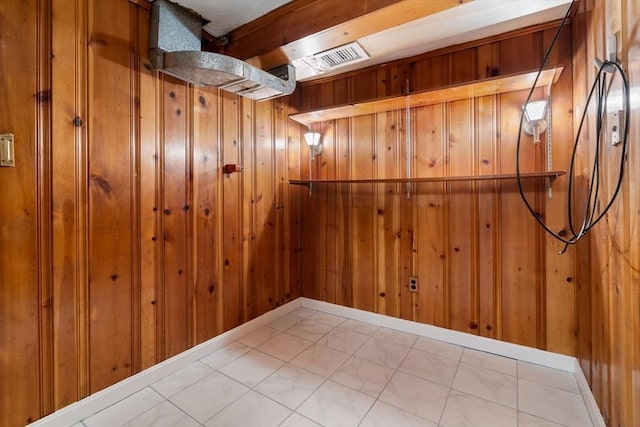below grade area with wooden walls and marble look tile flooring