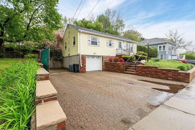 view of front of property with decorative driveway, an attached garage, stairway, and a chimney
