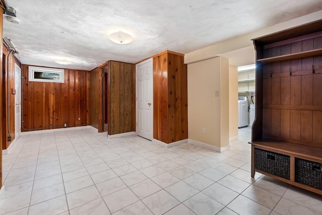 additional living space featuring washing machine and dryer, wood walls, and baseboards