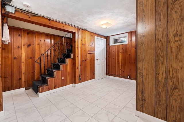 below grade area featuring wood walls, stairs, and tile patterned floors