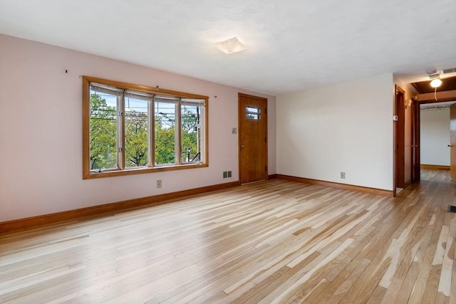 unfurnished living room featuring light wood-style floors, baseboards, and attic access