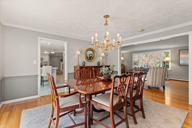 dining area featuring a baseboard heating unit, a notable chandelier, ornamental molding, and light wood-style floors