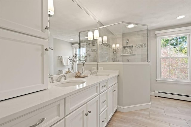 full bathroom featuring double vanity, a baseboard heating unit, a tile shower, and a sink