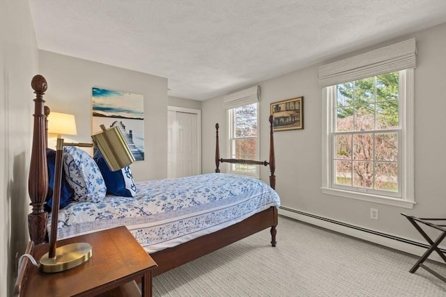 carpeted bedroom with baseboards, a baseboard radiator, and a closet