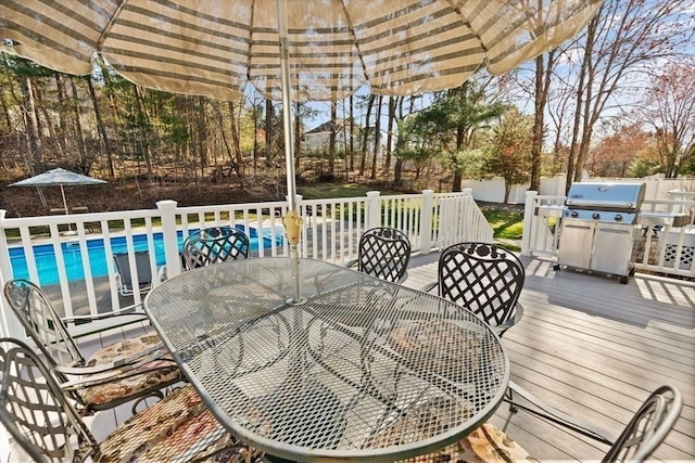 wooden terrace with outdoor dining area, fence, grilling area, and a fenced in pool